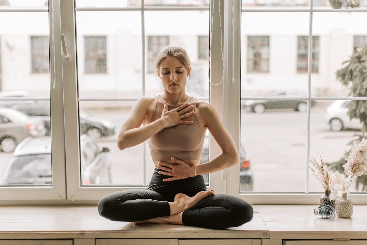 Woman seated with one hand on her chest and one on her belly, practicing a slow calming breath